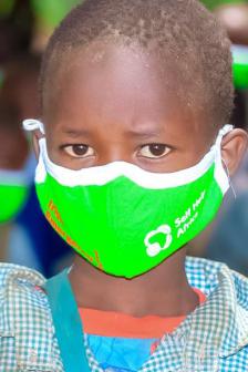 Small boy from kenya waring a bright green Covid face mask